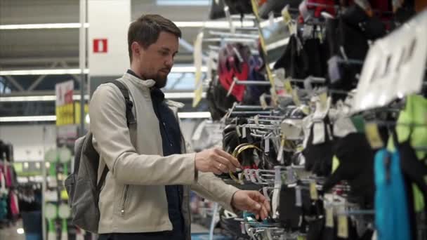 El cliente masculino se está probando unas gafas deportivas en una sala de comercio de una gran tienda — Vídeos de Stock