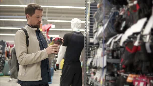 El deportista se refiere a una botella de plástico para el agua en una tienda de deportes — Vídeos de Stock