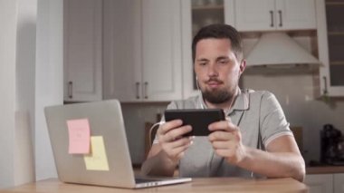 Yetişkin yakışıklı adam kulaklıklar giyen bir smartphone içinde ev, oynuyor