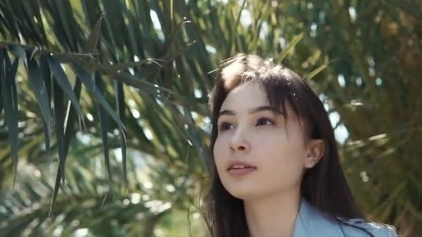 Одна веселая девушка гуляет в парке в летний день, трогает деревья — стоковое видео