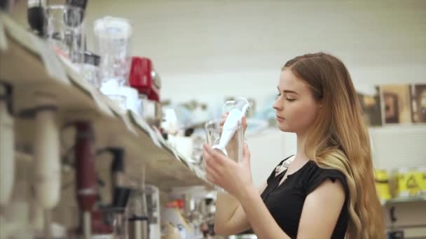 Klant van de jonge vrouw is het nemen van een blender met kom uit een rek in een winkel — Stockvideo