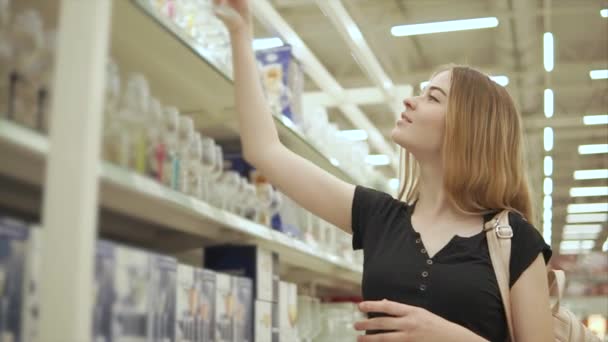 Chica alegre está bajando de un estante en una tienda una copa de vino — Vídeos de Stock