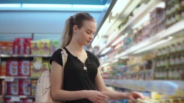 Genç Anne, bir kavanozu dükkanda bebek püresi ile bir etiket üzerinde yazıtlar okuyor