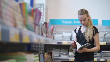 Öğrenci kız bir kırtasiye dükkanı defter sayfaları çevirme