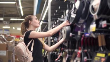 Gülümseyen kadın bir donanım mağaza yeni bir tava üzerinde arıyor