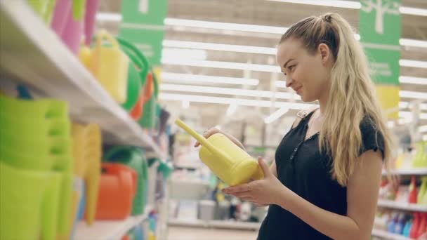 Schönes Mädchen kauft Wassersprenger. — Stockvideo