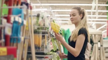 Ince sarışın kız bir süpermarket salonda bir bahçe komisyon arıyor