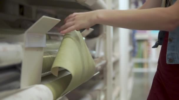 Женщина чувствует бумагу с обоями на витрине в магазине, крупным планом — стоковое видео