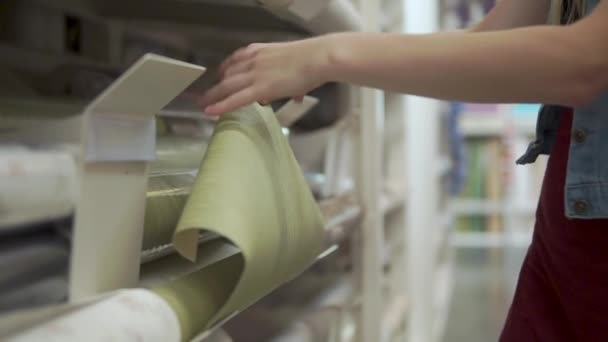 Vrouw is het gevoel van een paper van wandbekleding in showcase in een winkel, close-up — Stockvideo