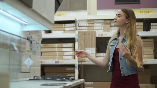 Vrouw op zoek naar nieuwe keuken set. — Stockvideo