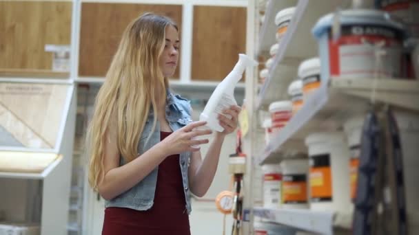 Visiteur femelle du magasin prend bouteille de rack et de lecture dans le hall avec des colorants — Video