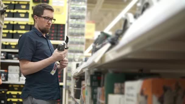 Mannelijke shopper neemt oscillerende machtshulpmiddel in een winkel van de bouw van extra — Stockvideo