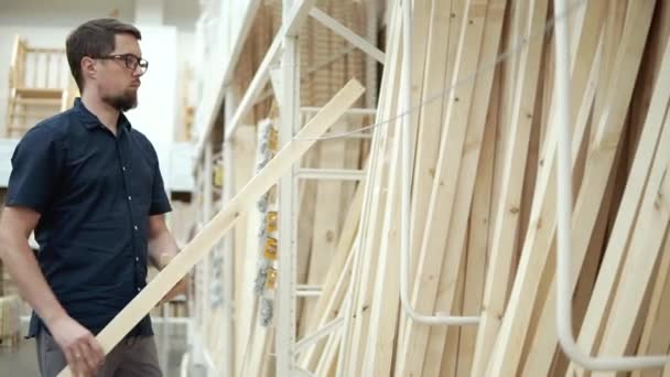 Constructor está seleccionando tablas de madera en una tienda de materiales de construcción — Vídeos de Stock