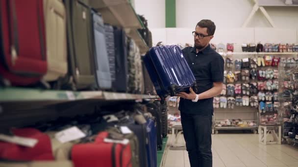 Maschio shopper sta prendendo valigia di plastica dallo scaffale in un supermercato, ispezionando — Video Stock