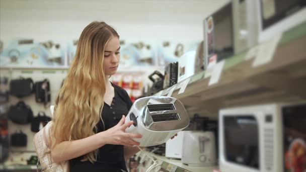 Jonge huisvrouw is inspectie van steekproef van broodrooster in een handel hal van hardware — Stockvideo