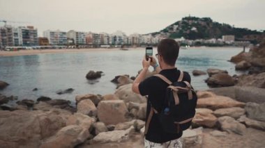 Turist kıyı üzerinde bir deniz fotoğrafları çekmek.