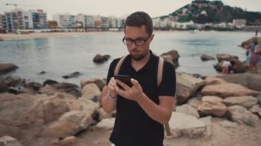 Adam bir kıyıya telefon bakıyor.