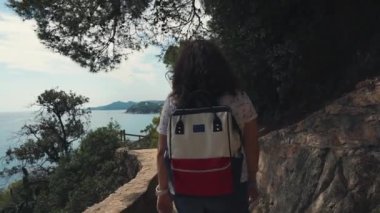 Esmer kadın yaz gününde üst deniz manzarası ile tepede gezinen, geri