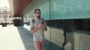 Alone erkek turist, telefon ekranına bakarak, sokakta yürüyor