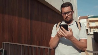 Sakallı erkek adam sokakta akıllı telefon ayakta bilgi arıyor
