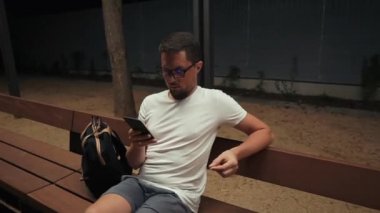 Yetişkin adam parkta akşam cep telefonu tarafından sosyal ağlar haber inceleyen