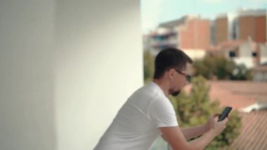 Erkek Kullanıcı akıllı telefonda mesajlar okuma, ekran kaydırarak, balkonda ayakta