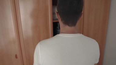 Adam dolap kapı açılıyor ve giysiler ile askıları alarak