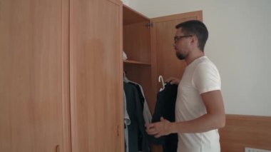 Genç ince adam onun dairesinde sabah zaman t-shirt seçiyor