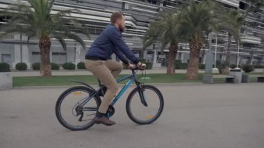 Genç sakallı adam yaz gününde Park alanında bisiklet sürme, yan görünüm