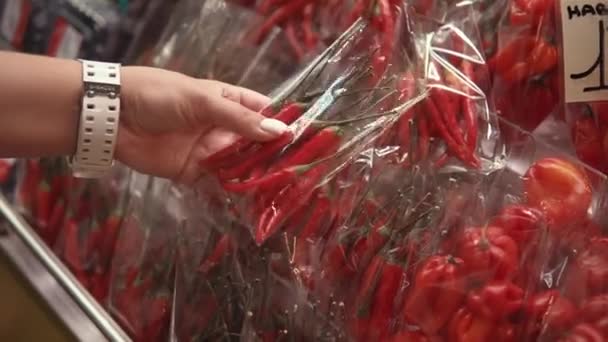 Weibliche Hand hält eine kleine Packung mit scharfen Chilischoten in einem Geschäft, Nahaufnahme, — Stockvideo