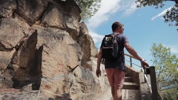Мужской турист поднимается по старой каменной лестнице, сделанной в скале в летний день — стоковое видео