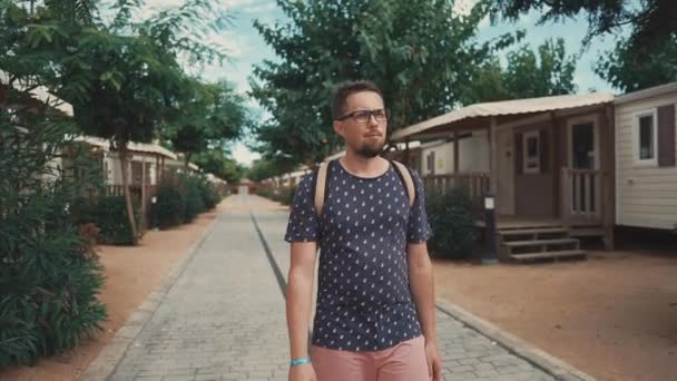 Selbstbewusster Mann spaziert im tropischen Garten in kleinem Touristendorf — Stockvideo
