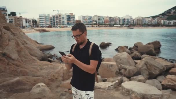 Homem em uma praia com um smartphone . — Vídeo de Stock