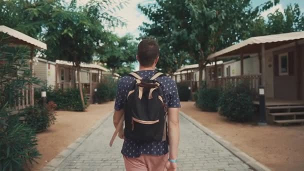 Yaz aylarında küçük ahşap evler kamp alanında adam gezinme arka görünümü — Stok video