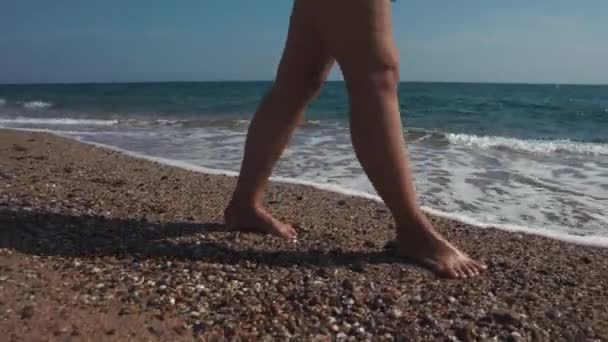Femeia mergând pe plaja cu pietricele . — Videoclip de stoc
