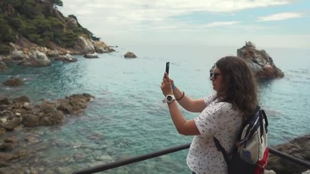 Turist kvinna tar bilder av fantastiska landskap med havet med smartphone — Stockvideo