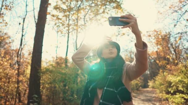 Menina bonito com um smartphone na natureza outono . — Vídeo de Stock