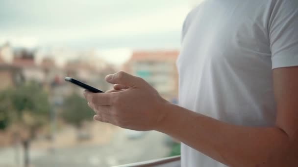 Man is typing message by smartphone, close-up of his hands, in daytime — Stock Video