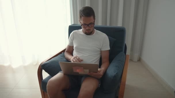 Solo uomo adulto sta lavorando con il computer portatile seduto in appartamento durante il giorno — Video Stock