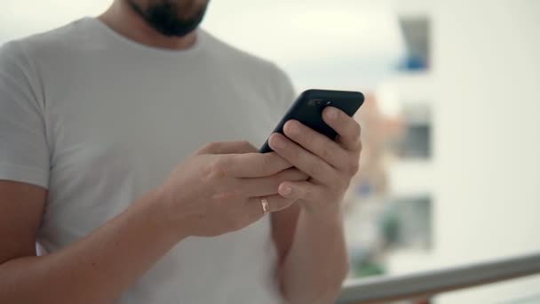 Ženatý muž drží mobilní telefon v ruce a dívá se na něj, zblízka — Stock video