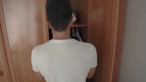 Single man is pulling out hanger with clothes and going to mirror in morning — Stock Video