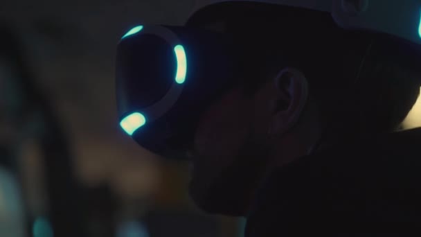 Человек с современными очками виртуальной реальности на глазах наблюдает внутри темной комнаты — стоковое видео