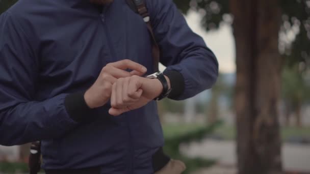 El hombre está controlando su reloj inteligente, el primer plano de sus manos, al aire libre — Vídeo de stock