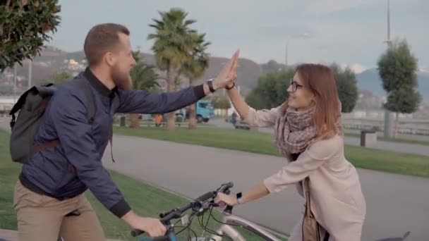 Twee gelukkige vrienden zeggen door en rijden fietsen aan verschillende kanten — Stockvideo