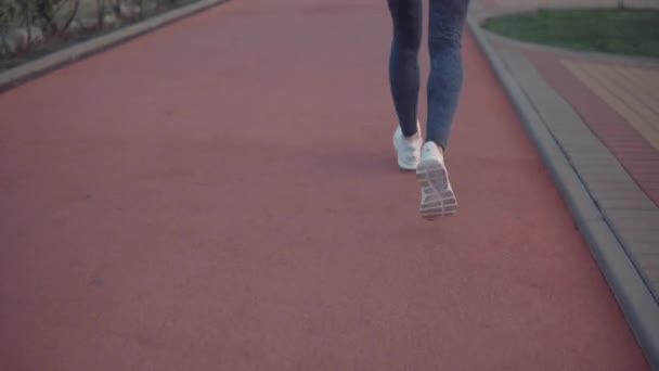 Gros plan de la femme sportive avec une silhouette mince courant à l'extérieur au crépuscule, vue de dos . — Video