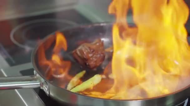 Повар трясет сковородку с горящим мясом и овощами, крупным планом — стоковое видео