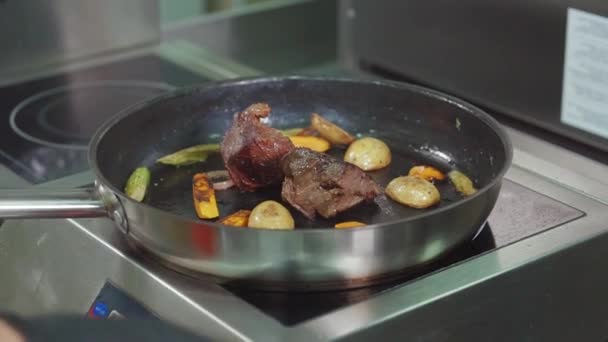 Meat and vegetables are roasting in frying pan on cooker, close-up — Stock Video