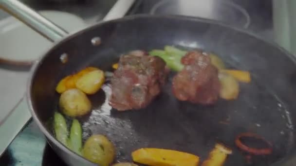 Кухар смажить м'ясний та овочевий рагу на сковороді з олією — стокове відео