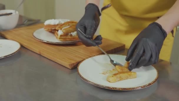 Кухар прикрашає вафлі кремом солодкими запеченими паличками, крупним планом — стокове відео