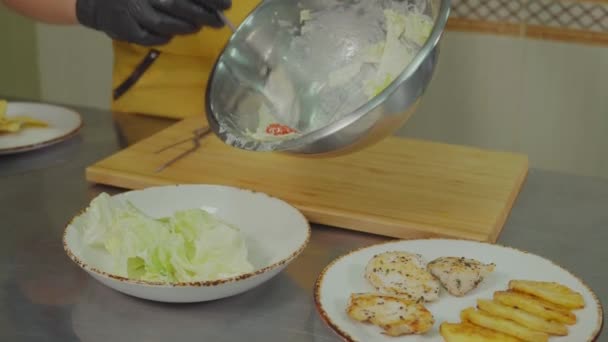 Cozinheiro profissional está colocando salada de legumes frescos em prato de servir na cozinha — Vídeo de Stock